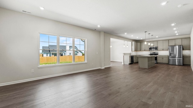 interior space with decorative light fixtures, dark wood-type flooring, gray cabinets, a center island, and appliances with stainless steel finishes