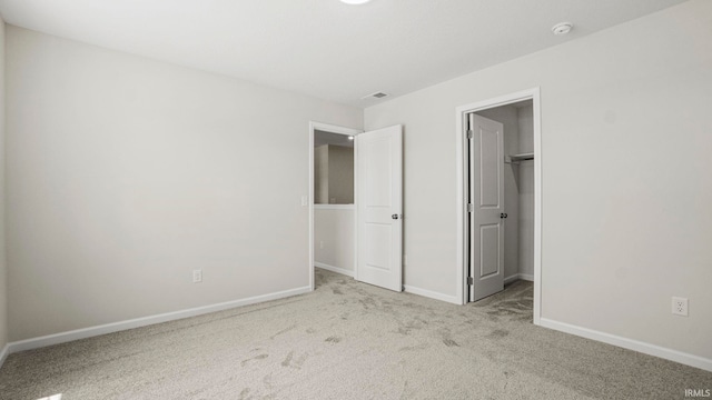 unfurnished bedroom with carpet, a closet, and a spacious closet