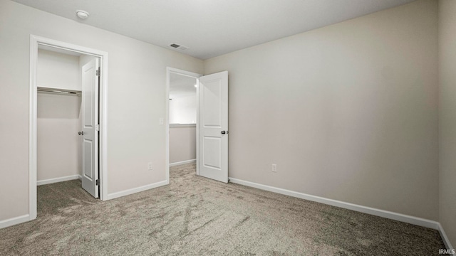 unfurnished bedroom with carpet, a closet, and a spacious closet