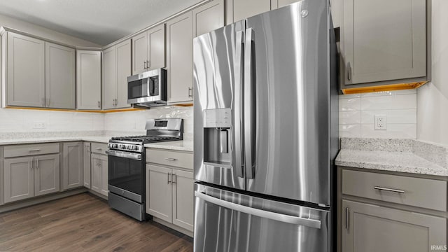 kitchen with appliances with stainless steel finishes, tasteful backsplash, dark hardwood / wood-style floors, and gray cabinets