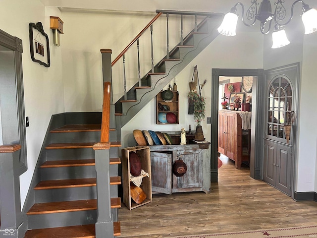 staircase with wood-type flooring and a chandelier