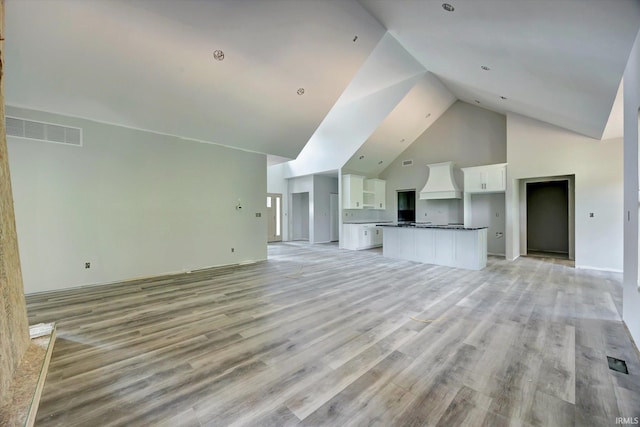 unfurnished living room featuring light hardwood / wood-style flooring and high vaulted ceiling