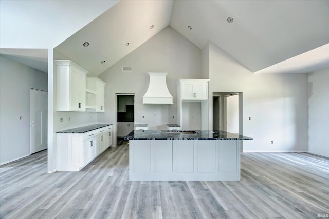 kitchen with high vaulted ceiling, light wood-type flooring, white cabinets, and a center island