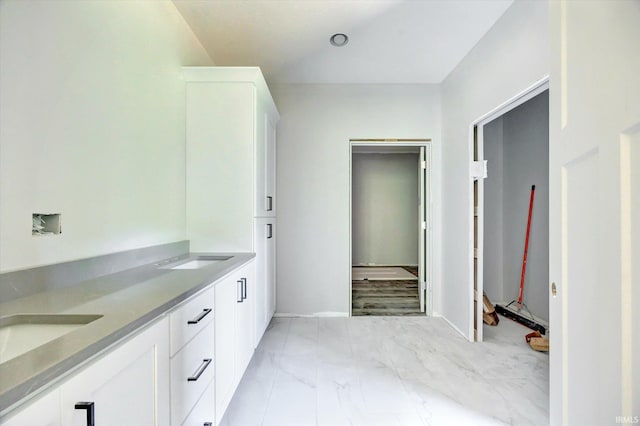 bathroom featuring a sink, marble finish floor, and double vanity