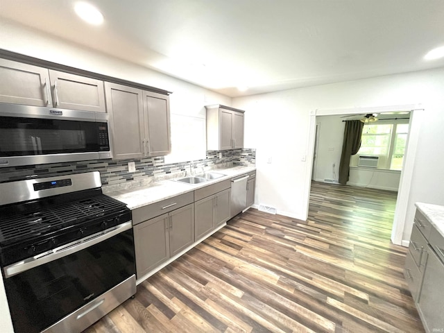 kitchen featuring appliances with stainless steel finishes, sink, tasteful backsplash, and wood-type flooring