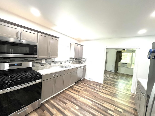 kitchen featuring appliances with stainless steel finishes, hardwood / wood-style floors, sink, tasteful backsplash, and ceiling fan