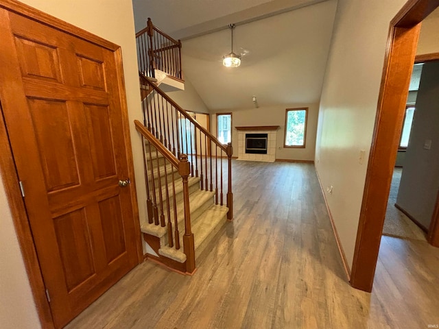 foyer with vaulted ceiling, wood-type flooring, and a tile fireplace