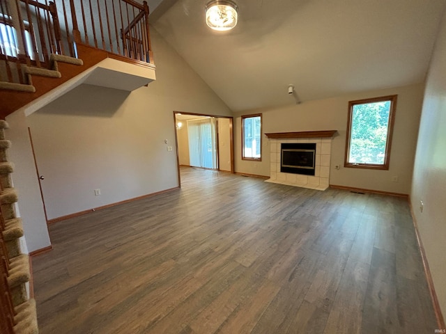 unfurnished living room featuring high vaulted ceiling, hardwood / wood-style flooring, and a tile fireplace