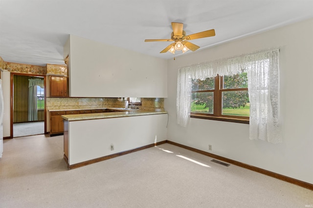 kitchen with light carpet, sink, ceiling fan, decorative backsplash, and kitchen peninsula