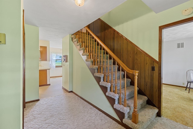 stairs featuring carpet flooring and wood walls