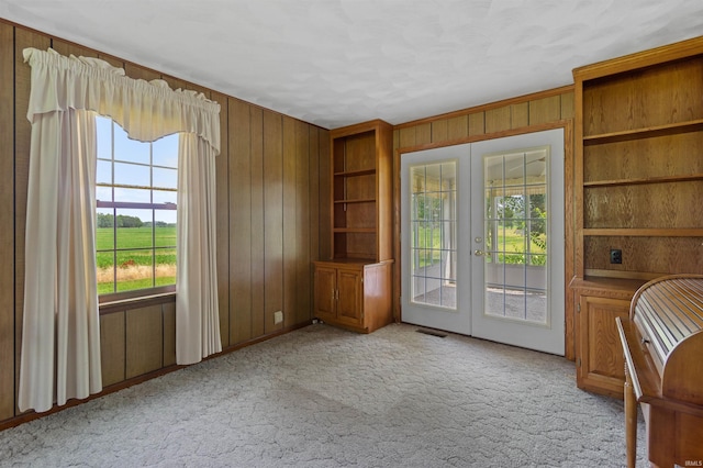 interior space featuring wooden walls, french doors, and light colored carpet