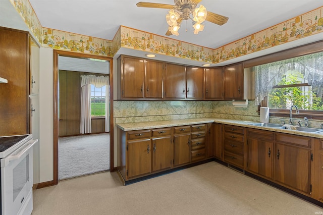 kitchen with electric range, sink, ceiling fan, tasteful backsplash, and light carpet