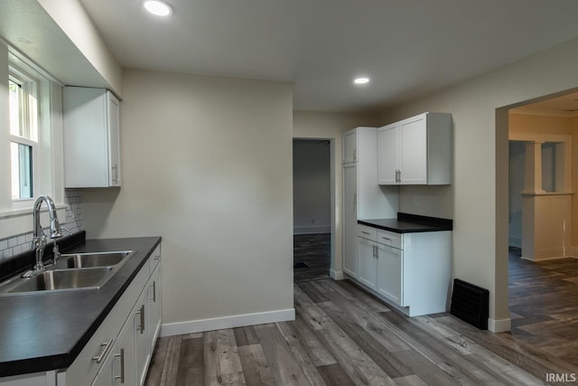 kitchen with sink, hardwood / wood-style flooring, and white cabinetry