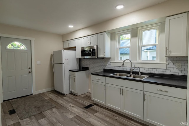 kitchen featuring white fridge, light hardwood / wood-style flooring, backsplash, white cabinetry, and sink