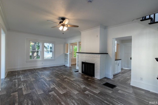 unfurnished living room with a brick fireplace, ornamental molding, ceiling fan, and dark hardwood / wood-style floors