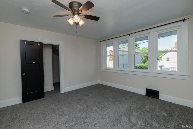 interior space with a closet, ceiling fan, carpet floors, and a walk in closet