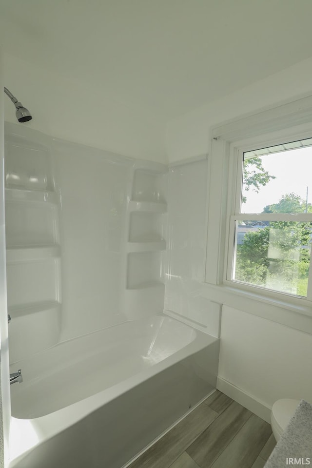 bathroom featuring  shower combination, hardwood / wood-style flooring, and toilet