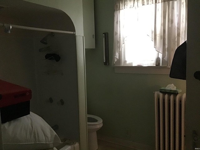 bathroom featuring toilet, radiator, and a shower