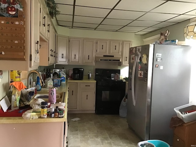 kitchen featuring sink, cream cabinets, black range oven, stainless steel refrigerator, and light tile patterned floors