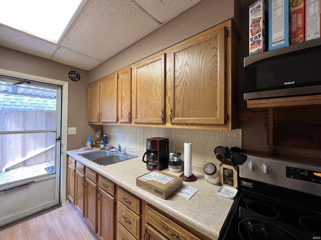 kitchen featuring a paneled ceiling, electric range oven, tasteful backsplash, sink, and light hardwood / wood-style floors