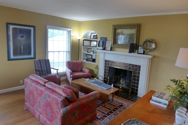 living room featuring hardwood / wood-style flooring, a tiled fireplace, and ornamental molding