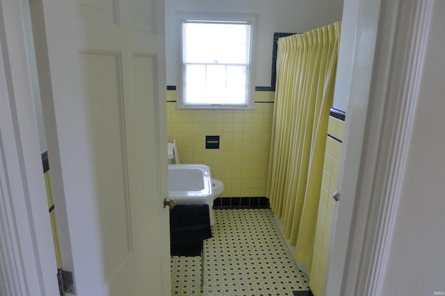 bathroom featuring tile walls and toilet