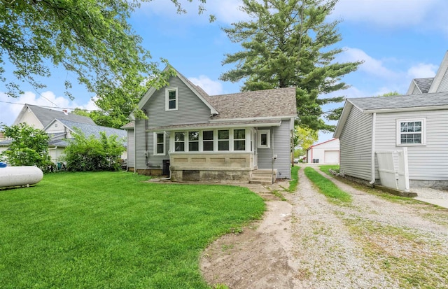 rear view of house featuring a lawn, a garage, and an outbuilding