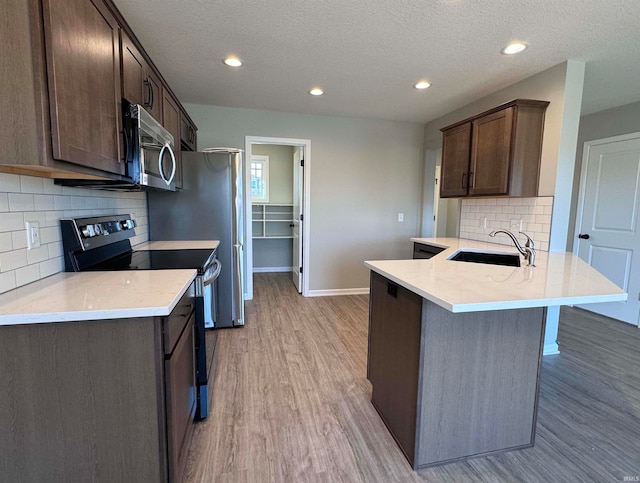 kitchen with sink, dark brown cabinets, light hardwood / wood-style flooring, kitchen peninsula, and electric stove