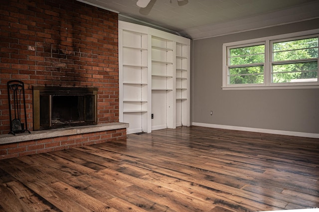 unfurnished living room with a brick fireplace, ceiling fan, dark hardwood / wood-style flooring, and ornamental molding