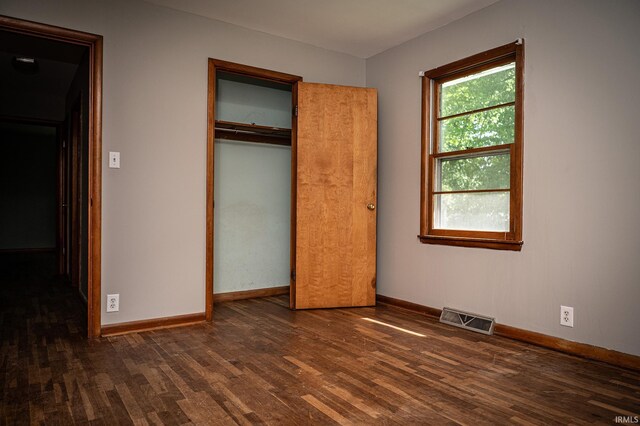 unfurnished bedroom featuring a closet and dark wood-type flooring