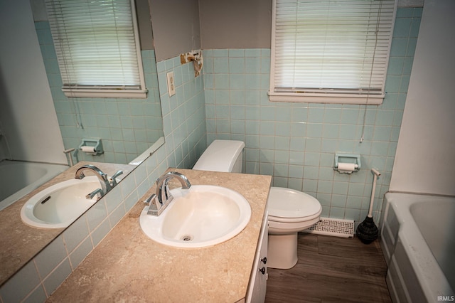 bathroom with wood-type flooring, toilet, tile walls, and a bathing tub