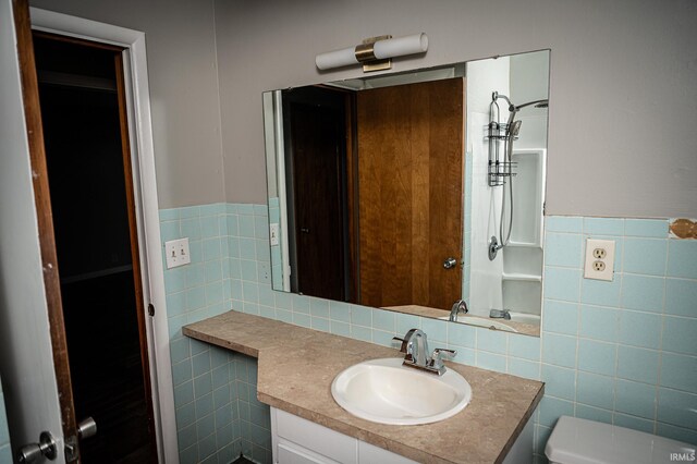 bathroom with vanity, toilet, and tile walls