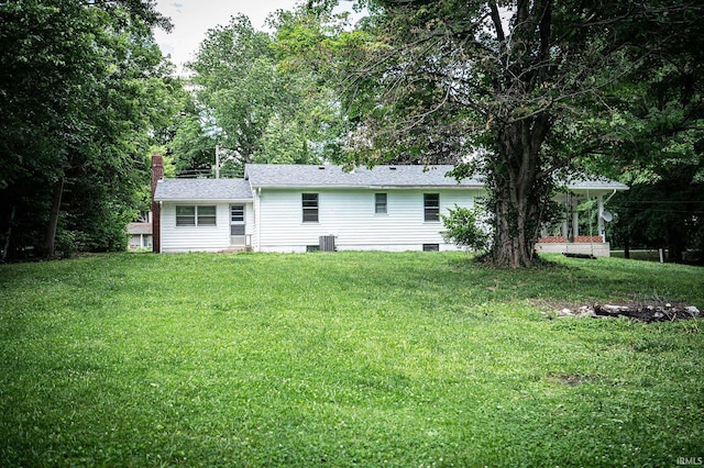 rear view of house with central air condition unit and a yard