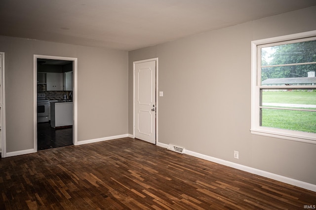 unfurnished room featuring dark wood-type flooring and a healthy amount of sunlight