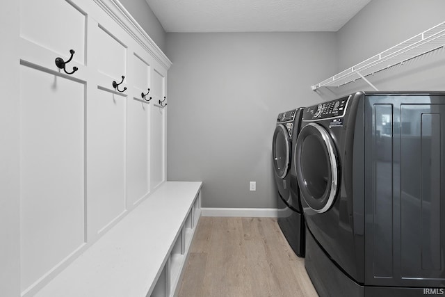 laundry area with independent washer and dryer, a textured ceiling, and light hardwood / wood-style floors