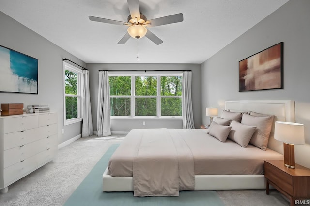 carpeted bedroom featuring multiple windows and ceiling fan