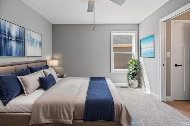 bedroom with ceiling fan, carpet, and a textured ceiling