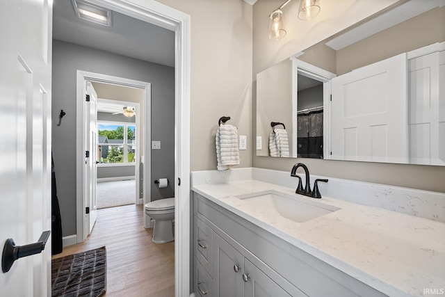 bathroom with toilet, hardwood / wood-style flooring, vanity, and walk in shower