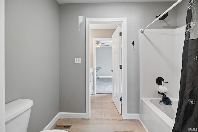 bathroom featuring toilet, shower / bath combination with curtain, and hardwood / wood-style floors