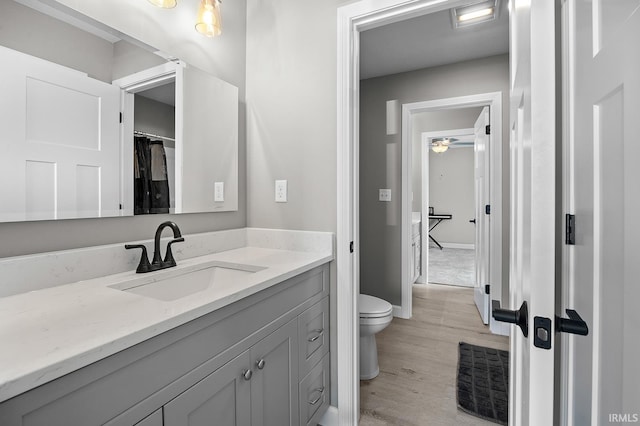 bathroom featuring toilet, wood-type flooring, vanity, and ceiling fan