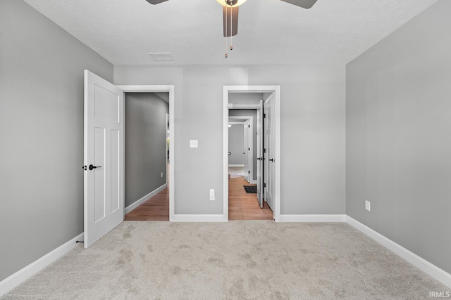 unfurnished bedroom with ceiling fan, a textured ceiling, and light colored carpet