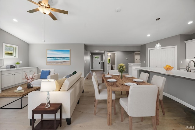 dining space featuring sink, ceiling fan, light hardwood / wood-style floors, and vaulted ceiling