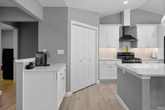 kitchen with range, wall chimney exhaust hood, white cabinets, and light hardwood / wood-style floors