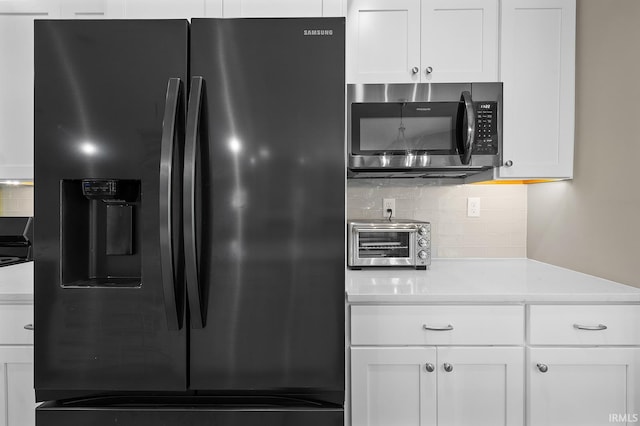 kitchen with white cabinetry, backsplash, black fridge with ice dispenser, and light stone counters