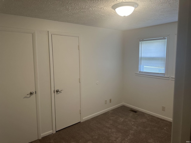 unfurnished bedroom featuring baseboards, visible vents, a textured ceiling, and carpet flooring