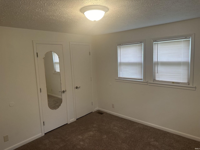 unfurnished bedroom with a closet, baseboards, dark colored carpet, and a textured ceiling