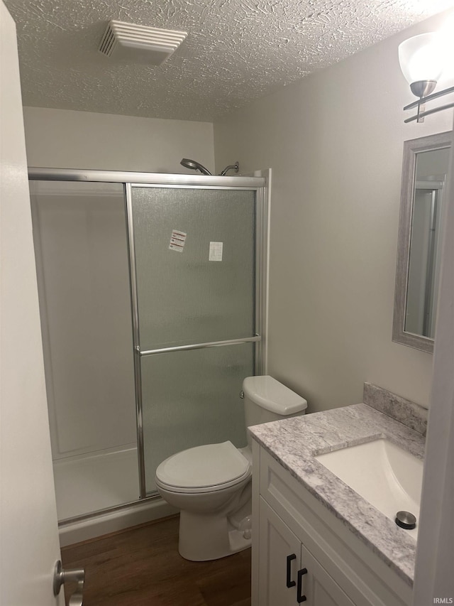 full bath featuring a stall shower, a textured ceiling, vanity, and wood finished floors