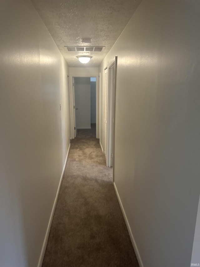 hall with baseboards, carpet, visible vents, and a textured ceiling