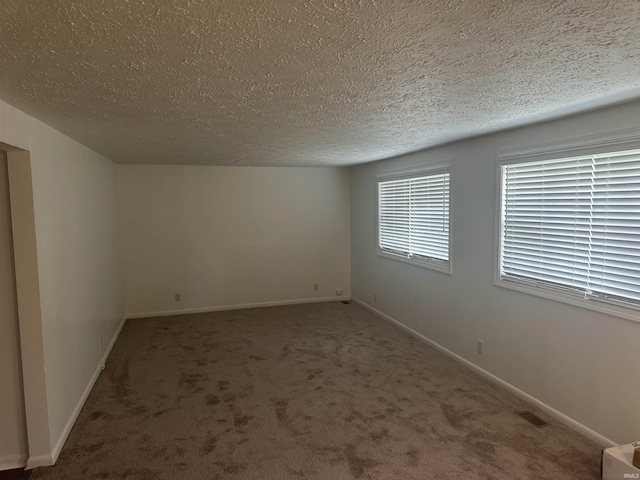 spare room with carpet, visible vents, baseboards, and a textured ceiling