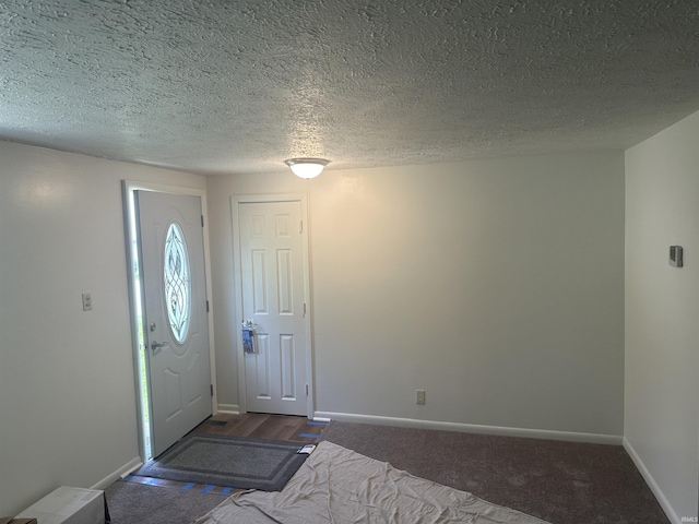 foyer featuring a textured ceiling, carpet, and baseboards